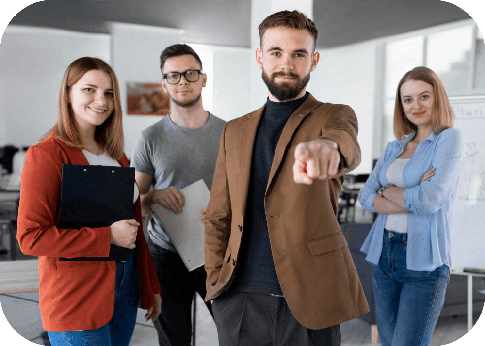 A group of crypto SEO experts in a lively office, with one employee confidently pointing at the camera, engaging readers to join their blockchain project journey, surrounded by colleagues and screens displaying SEO charts and blockchain analytics.